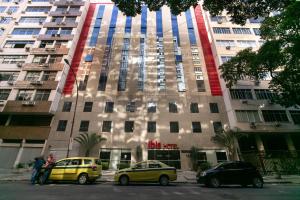 two cars parked in front of a tall building at ibis Copacabana Posto 2 in Rio de Janeiro