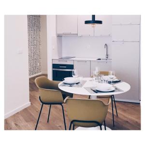 cocina blanca con mesa blanca y sillas en Casas Á Beira - Apartamentos en Pontevedra