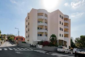 a large white building with cars parked in front of it at Alegria I by An Island Apart in Funchal
