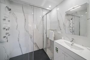 a white bathroom with a shower and a sink at Alegria I by An Island Apart in Funchal +18 photos