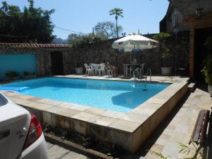 a swimming pool with an umbrella in a yard at Nacif's Suites in Rio de Janeiro