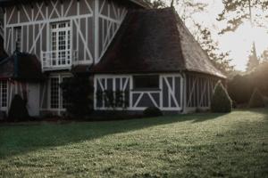 una casa blanca con techo de gambrel en el césped en La Dime de Giverny - Cottages, en Giverny