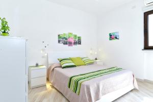 a white bedroom with a bed with green pillows at Il Profumo di Capri in Massa Lubrense