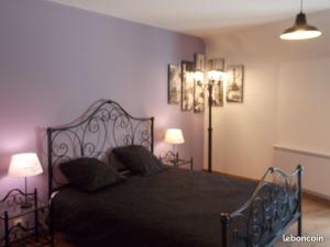 a bedroom with a black bed with two lamps at Le gîte du bois sebille in Verdelot