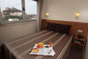 Una habitación de hotel con una cama con una bandeja de comida. en Hotel São Francisco, en Leiria
