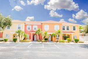 a building with palm trees in front of a parking lot at Berkley Lake Townhomes in Kissimmee