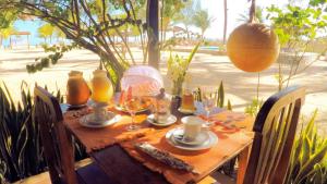 uma mesa de madeira com um conjunto de mesa com copos de vinho em Pousada Recanto da Praia em São Miguel do Gostoso