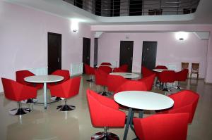a room filled with tables and red chairs at Hotel Okriba in Kutaisi