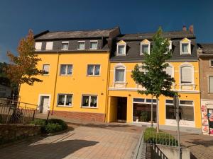 ボッパルトにあるHotel Sonnenhofの木の目の前の黄色い建物