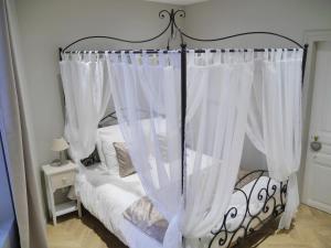 Una cama con cortinas blancas en un dormitorio. en Le Secret de Louise, en Épernay