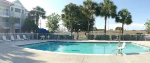 a swimming pool with a chair and palm trees at InTown Suites Extended Stay Orlando FL - Universal in Orlando