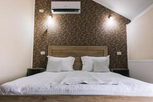 a bed with white sheets and pillows in a bedroom at La Tusi Lovrin in Lovrin