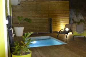 a patio with a hot tub and chairs on a deck at LES VILLAS TARA ET ANAIS in Les Trois-Îlets