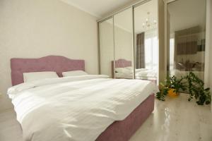 sypialnia z dużym białym łóżkiem z fioletowym zagłówkiem w obiekcie ЖК Славутич апарти w Kijowie