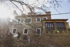 una casa de piedra con dos personas de pie delante de ella en Dar Ait Bouguemez en Azilal