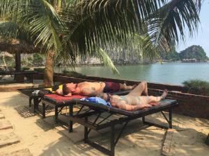 
a person laying on a bench next to a body of water at Cat Ba Sandy Beach Resort in Cat Ba
