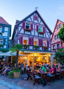 een groep mensen die aan tafels voor een gebouw zitten bij Berne's Altstadthotel in Besigheim