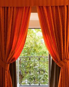 a window with orange curtains and a balcony at Locanda San Cosimato in Rome