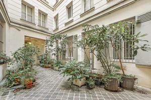 une cour avec des plantes en pot dans un bâtiment dans l'établissement Pick A Flat's Apartment in Louvre Saint Honoré, à Paris