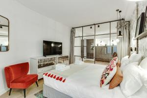 a bedroom with a large bed and a red chair at Pick A Flat's Apartment in Louvre Saint Honoré in Paris