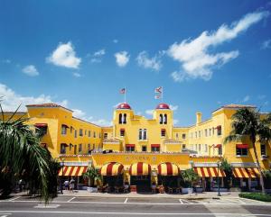 Un grand bâtiment jaune avec des drapeaux en haut dans l'établissement Casa Historica, a cozy 1940 cottage in Delray Beach, FL, à Delray Beach