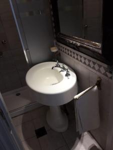 uma casa de banho com um lavatório branco e um espelho. em Silencioso departamento antiguo em Buenos Aires