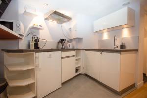 a kitchen with white cabinets and a sink at Le Duplex in Versailles