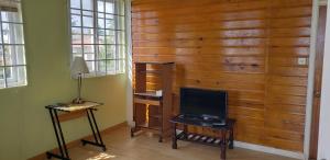 Cette chambre dispose d'un mur en bois, d'une télévision et d'un bureau. dans l'établissement Unit 5/6 Private Apartment - Roseau, à Roseau