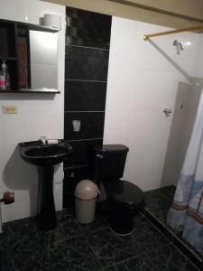 La salle de bains est pourvue de toilettes noires et d'un lavabo. dans l'établissement Un lugar para descansar, à Palestina