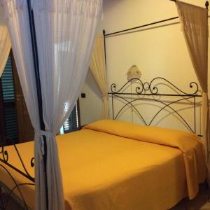Schlafzimmer mit einem Bett mit gelber Bettwäsche und Vorhängen in der Unterkunft Bed&Breakfast Castagna in Carlopoli