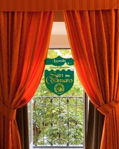 a window with orange curtains in front of a window at Locanda San Cosimato in Rome