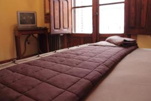 Cette chambre comprend un grand lit violet et une fenêtre. dans l'établissement Hostería de la Galería Cerdán, à Talavera de la Reina