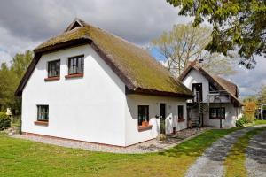 ein altes Haus mit einem Strohdach in der Unterkunft Ferienhaus und -wohnung unterm Reetdach in Woorke in Hof Patzig