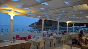 un restaurante en la playa con mesas y sillas en Il Gabbiano, en Stalettì