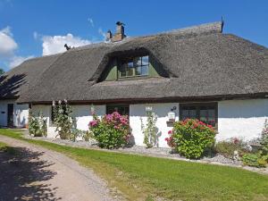 a white house with a thatched roof and flowers at Ferienhaus und _wohnung unterm Ree in Hof Patzig