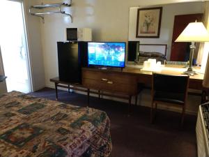 Cette chambre dispose d'un bureau, d'une télévision et d'un lit. dans l'établissement Southwest Motel, à Grants