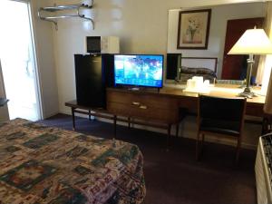 a hotel room with a desk with a television and a bed at Southwest Motel in Grants