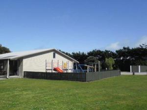a white house with a playground in a yard at Greymouth Kiwi Holiday Park & Motels in Greymouth +20 photos