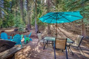 un patio con mesa, sillas y sombrilla en Tasteful Truckee Cabin, en Truckee