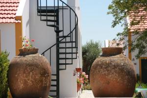 two large vases sitting next to a spiral staircase at Horta Da Vila in Alvito