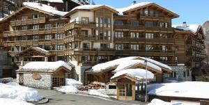 a large wooden building with snow on it at Hôtel Les Barmes De l'Ours in Val-d'Isère