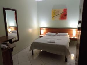Una habitación de hotel con dos camas y un espejo. en Pousada Cavaleiros, en Macaé