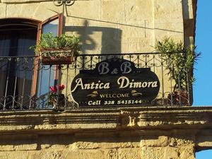 a sign on a building with plants on a balcony at Antica Dimora Historic Building in Enna