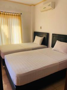 - 2 lits installés l'un à côté de l'autre dans une chambre dans l'établissement Pondok Sunrise 2, à Gili Trawangan
