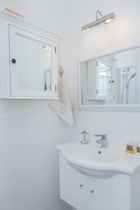La salle de bains blanche est pourvue d'un lavabo et d'un miroir. dans l'établissement Papanui Paris inspired Apartment, à Christchurch