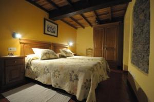 a bedroom with a large bed with a white blanket at Apartamentos Rurales Romallande in Puerto de Vega