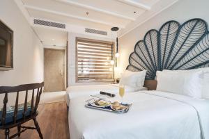 a hotel room with a bed with a tray of food on it at Sofiana My Khe Hotel & Spa- Rooftop Pool Bar in Danang