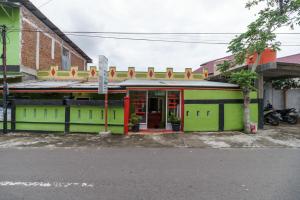 a green building with a red door on a street at RedDoorz Syariah near Paradiso Beach Sabang in Sabong