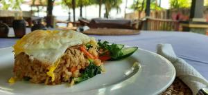 a white plate with a sandwich on a table at Bali Bhuana Beach Cottages in Amed