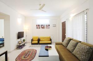 uma sala de estar com um sofá e uma televisão em Qualtems Guest House em Bangalore